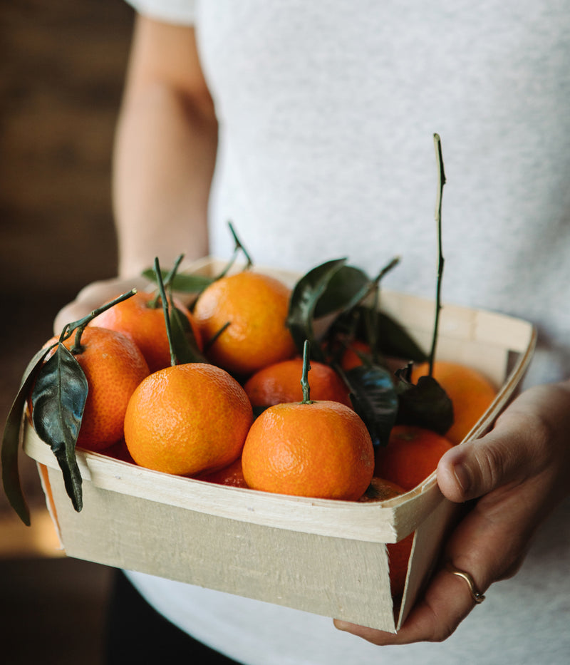 A person holding a box of fruit