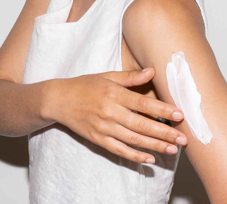 A close-up of a woman applying body lotion on her arm