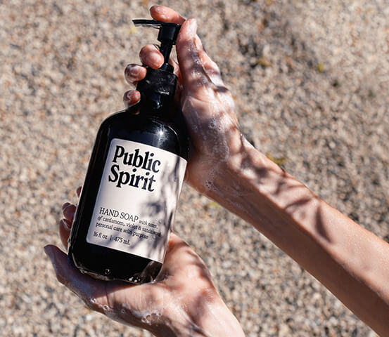 Someone holding Public Spirit Hand Soap Outside with Shadows from Tree