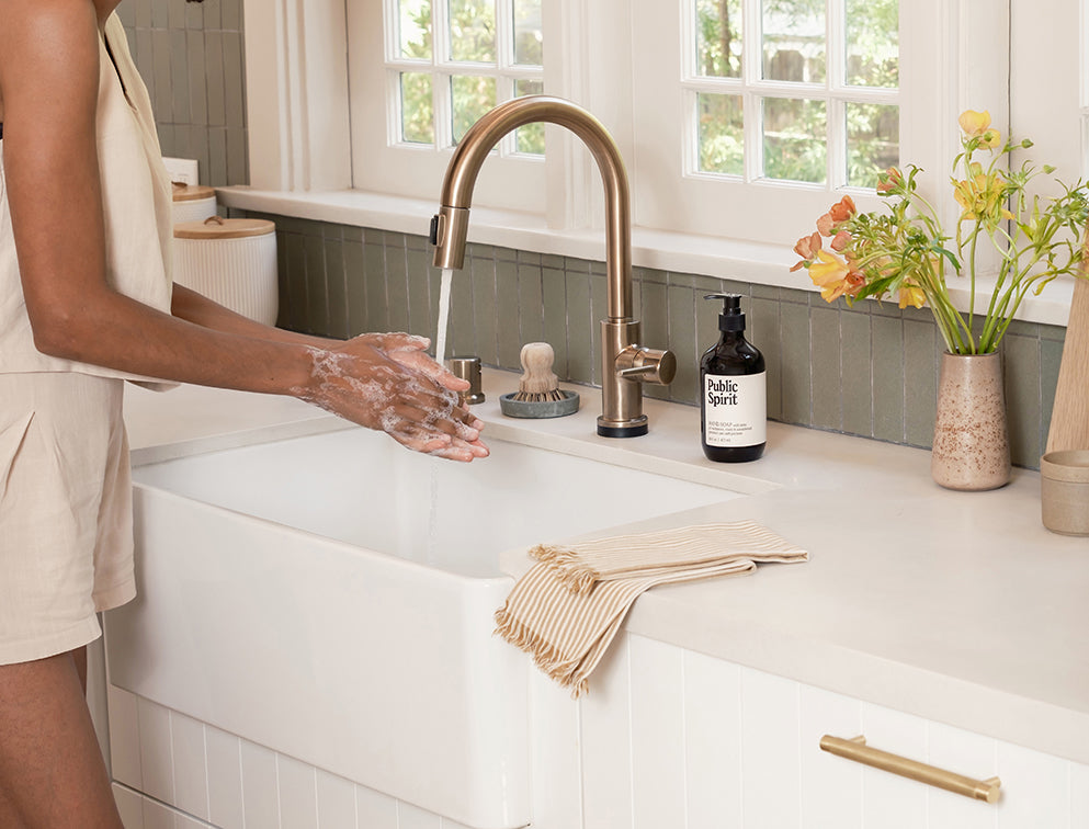 A woman washing her hands with Public Spirit hand soap in kitchen